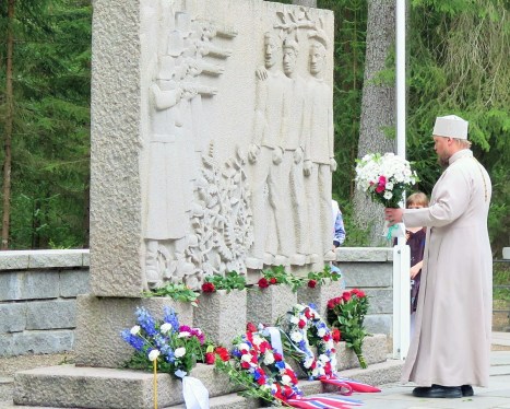 Возложение священником цветов к памятнику узникам Фалстада